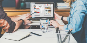 Businessman and businesswoman sitting at table in front of laptop and working.Graphs,charts and diagrams on PC screen. martech tools